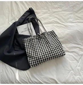 Detail of black and white checkered tote bag with a delicate ribbon bow on white sheets