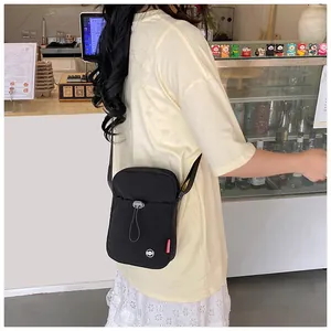 Détail d'un petit sac bandoulière noir en nylon avec cordon et étiquette rouge mode