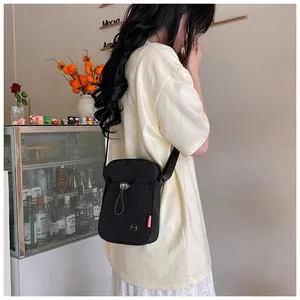 Détail d'un sac bandoulière noir en nylon avec étiquette fashion et cordon sur modèle
