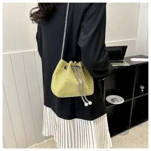 Detail van een felgele strass emmertas met zilveren ketting en parel trekkoord