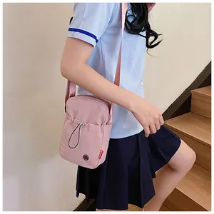 Gros plan sur le sac de téléphone rose en nylon avec bandoulière réglable et étiquette