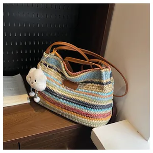 Detail of colorful striped straw tote bag with PU straps and a cute plush cloud charm
