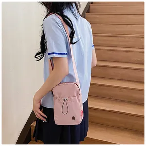 Détail de la pochette bandoulière rose en toile avec étiquette fashion et poche avant