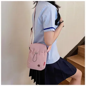 Détail d'un sac bandoulière rose en tissu avec cordon de serrage sur escalier