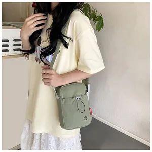 Détails du sac bandoulière en toile vert sauge avec sangle réglable et poche à cordon
