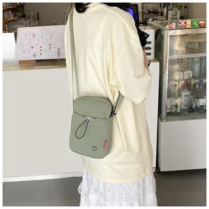 Détail du sac à bandoulière en nylon vert avec étiquette mode et cordon de serrage