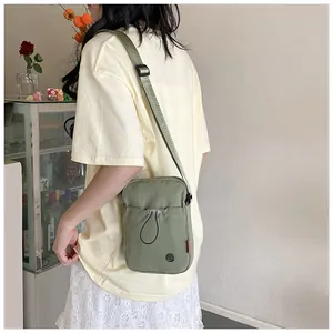 Vue détaillée du sac bandoulière en nylon vert foncé avec sangle large et poche frontale