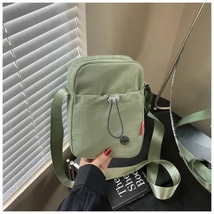 Gros plan du sac à bandoulière en nylon vert clair avec poche à cordon réglable