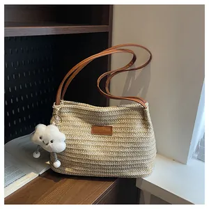 Detail of hand-woven straw tote with leather label and cute white cloud pendant