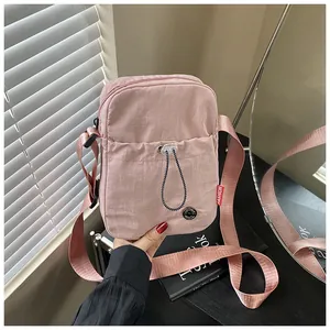 Détail d'un sac bandoulière rose en nylon avec sangle réglable et étiquette mode