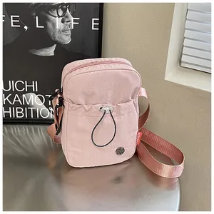 Détail d'un mini sac bandoulière rose en nylon avec poche à cordon et étiquette