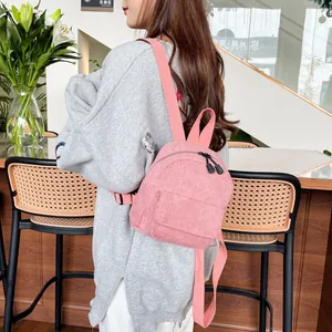 Detailed close-up of pink corduroy mini backpack texture and front zipper pocket