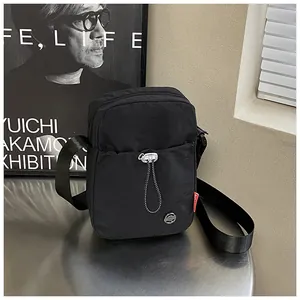 Détail d'un sac bandoulière en nylon noir avec poche zippée sur table métallique