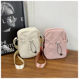 Détail de sacs bandoulière légers en nylon beige et rose avec étiquettes mode