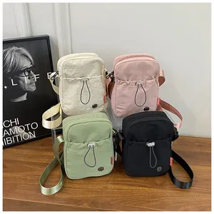 Détail de quatre mini sacs bandoulière en nylon de couleurs crème, rose, vert et noir
