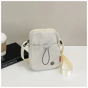 Détail d'un sac pour téléphone en nylon beige avec poche à cordon et sangle