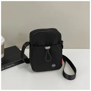 Détail d'un sac à bandoulière en nylon noir avec sangle réglable et poche zippée