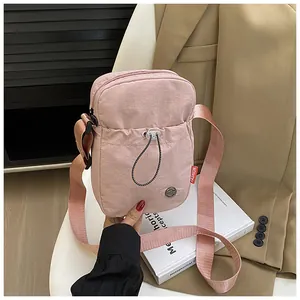 Détail du sac de téléphone rose en nylon avec poche à cordon et bandoulière réglable