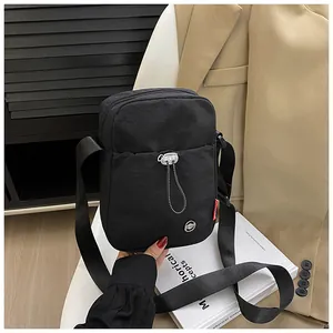 Détail de la mini sacoche en nylon noir avec poche frontale à cordon et bandoulière réglable