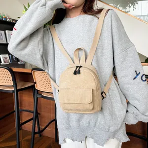 Detailed view of beige corduroy mini backpack on a person showing its compact size