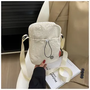Détail d'un sac bandoulière en nylon crème avec étiquette mode dans un décor élégant