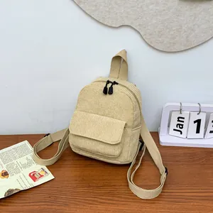 Detail of beige corduroy mini backpack with front flap pocket on a wooden desk