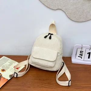Detailed view of mini corduroy backpack with front flap pocket on a wooden surface