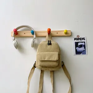 Detailed close-up of a mini corduroy backpack in beige featuring a zipper and front flap pocket