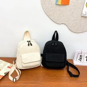 Detail of mini corduroy backpacks in black and cream with soft ribbed texture and straps
