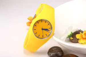 Detail of yellow silicone Geneva watch with dark blue markers on white ceramic background