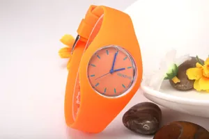 Macro view of bright orange quartz watch with blue hands on a white surface