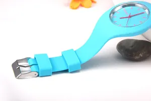 Detail of light blue Geneva silicone watch with red markers next to flowers and stones