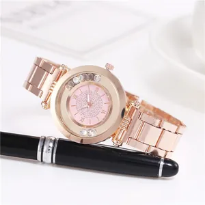 Detail der roségoldenen Uhr mit Kristallen und beweglichen Strasssteinen auf weißem Tisch