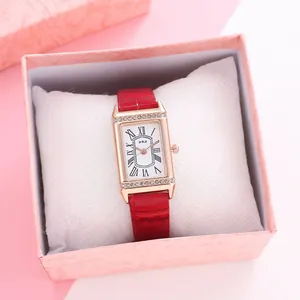Detail of square rose gold watch with rhinestones and red strap in a pink gift box