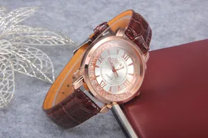 Detailed close-up of a rose gold quartz watch with Roman numerals and a brown leather strap