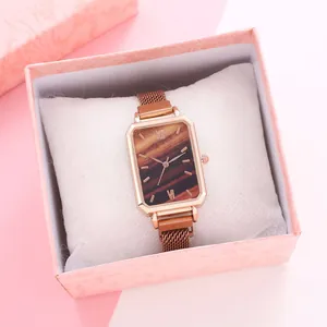 Close-up of elegant rose gold rectangular watch with wood grain dial in a gift box