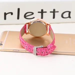 Detail view of the rose gold watch case back and pink leather strap on a smooth surface