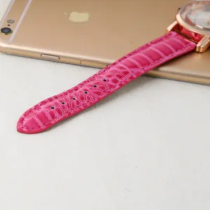 Detail of rose red leather watch strap with crocodile pattern and rose gold Roman dial