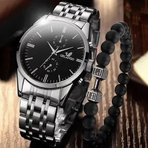 Close-up of silver steel watch and black matte beaded bracelet on a dark wood background