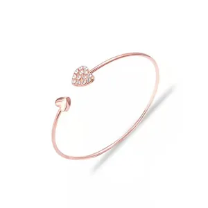 Detail of rose gold open bracelet with double heart charms and sparkling crystals