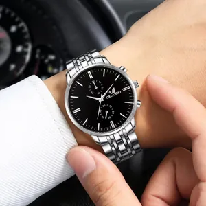 Close-up of men's steel band watch with black dial worn in a car interior setting