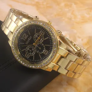 Gold stainless steel quartz watch with black dial and rhinestone bezel on a marble background