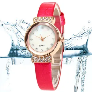 Detail of rose gold watch bezel with rhinestones and red leather texture strap with water splash