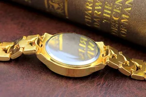 Details von goldenem Uhrenarmband und Edelstahldeckel auf Lederhintergrund