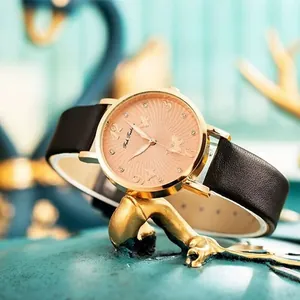 Elegant women's watch with golden butterfly dial and black leather strap on decorative stand