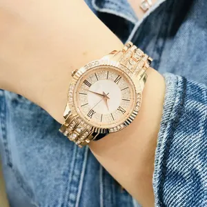 Detail of rose gold quartz watch with rhinestones and Roman numerals on denim background