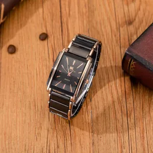 Macro detail of men's square quartz watch with black sunray dial on wooden desk