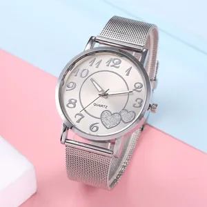 Détail de la montre argentée à maille avec motifs de cœur et cadran quartz