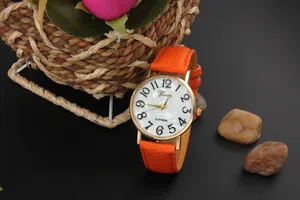 Close-up of bright orange litchi texture leather strap and golden quartz watch case