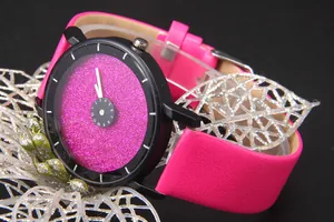 Dettaglio dell'orologio rosa glitterato con scala numerica rotante e cinturino in pelle